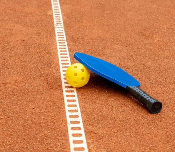 a tennis racket and ball on a clay court
