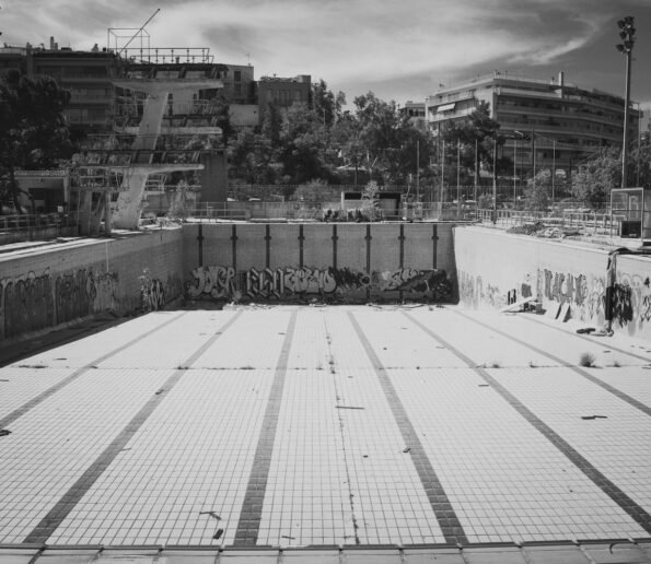 An abandoned swimming pool is empty and depressed.